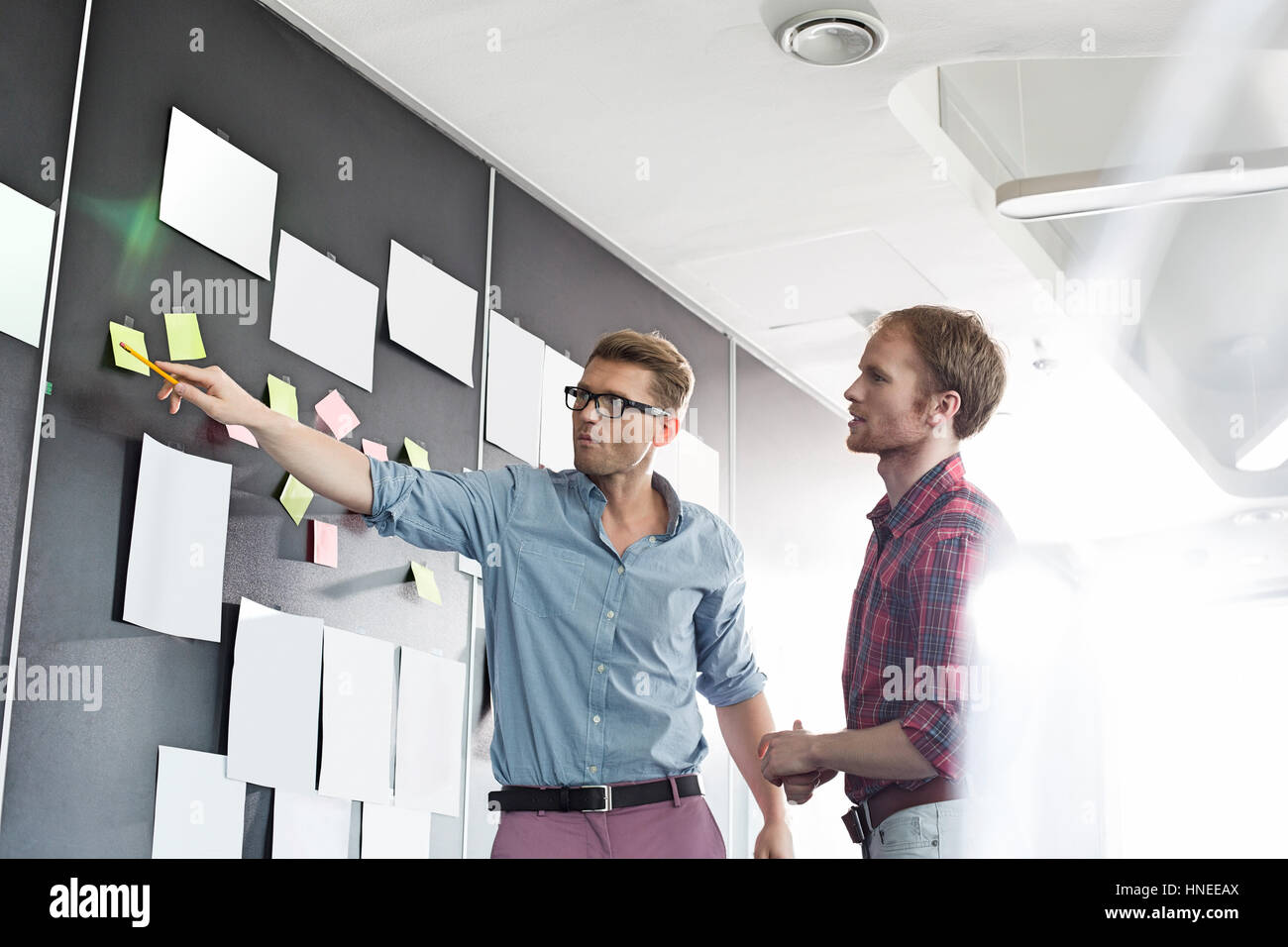 Kreative Unternehmer diskutieren über klebrige Papier an der Wand im Büro Stockfoto