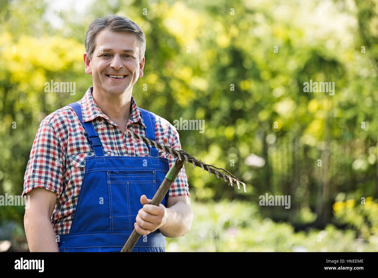 Porträt von lächelnden Gärtner hält Rake in Gärtnerei Stockfoto