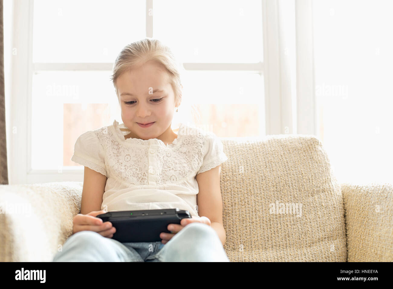 Niedliche Mädchen tragbare Videospiel zu Hause spielen Stockfoto