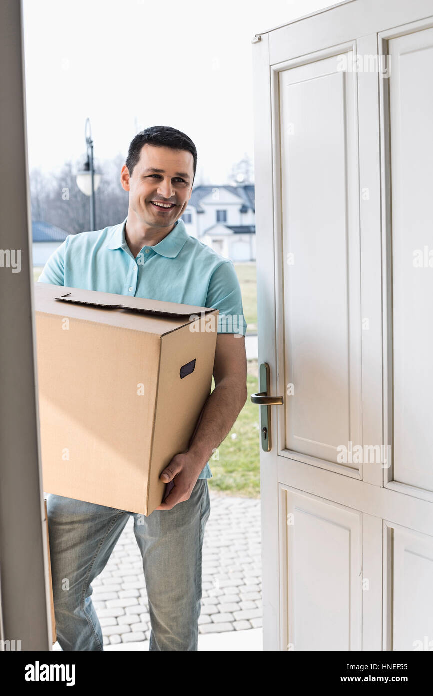 Glücklicher Mann mit Karton während der Eingabe neuen Haus Stockfoto