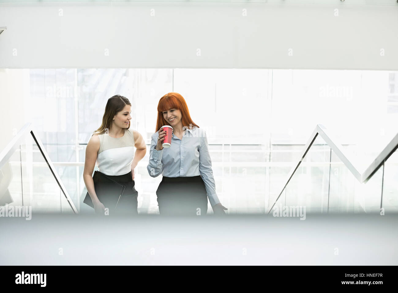 Geschäftsfrauen Kaffeetrinken während der Bewegung Stufen im Büro Stockfoto