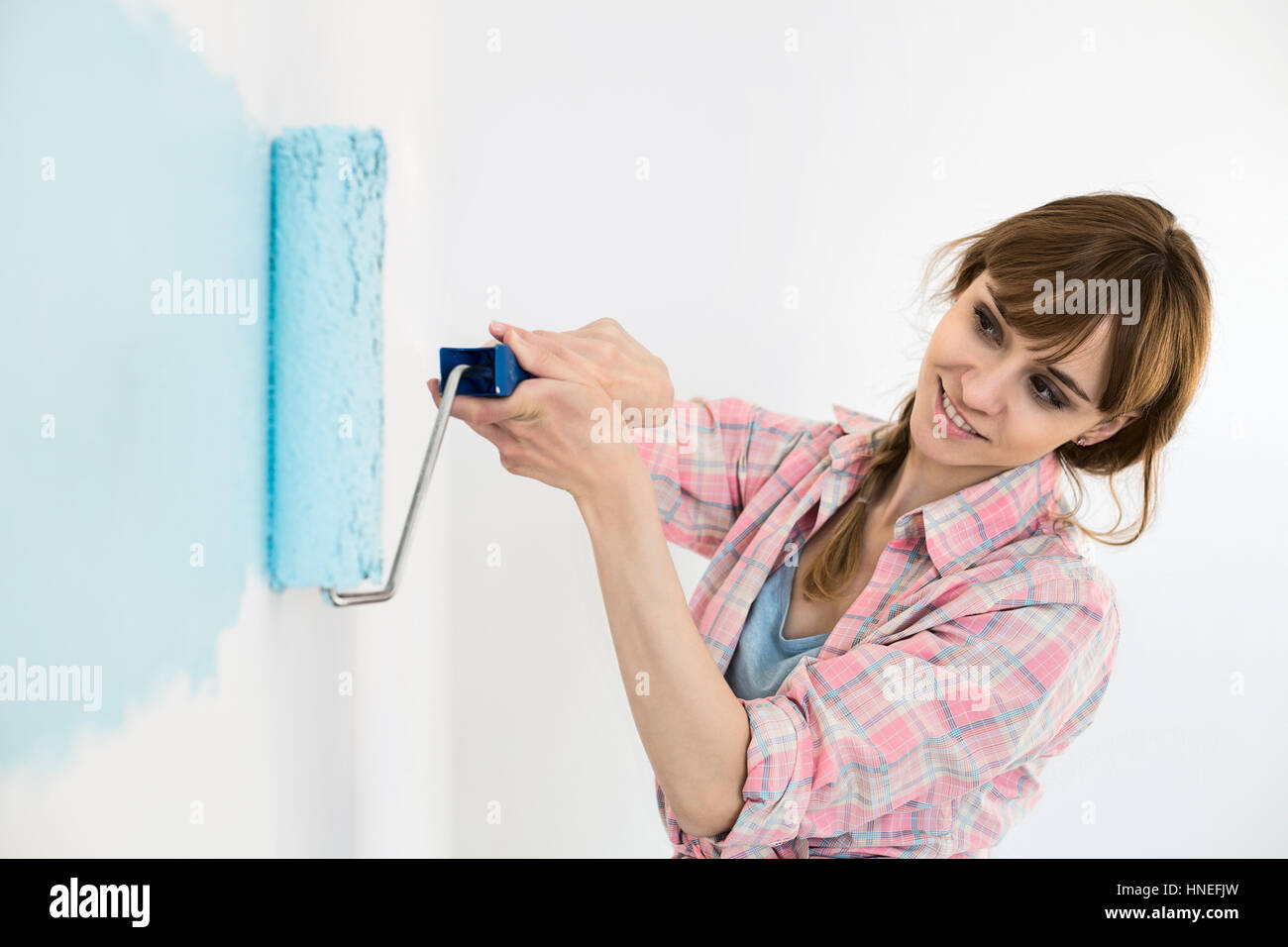 Schöne Frau Malerei Wand mit Farbroller Stockfoto