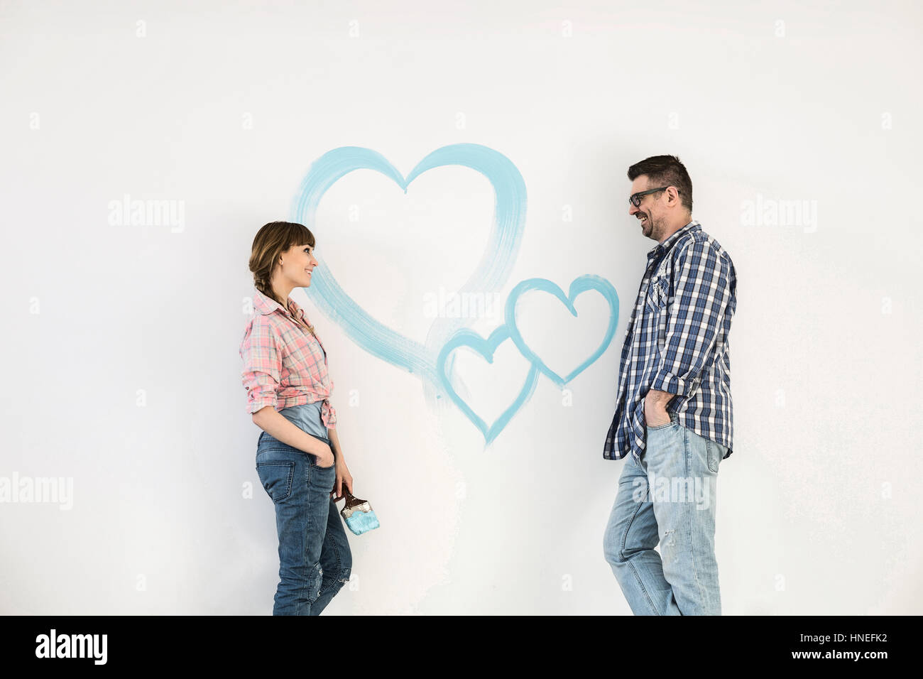 Mid-Adult paar sahen einander mit gemalten Herzen an Wand Stockfoto