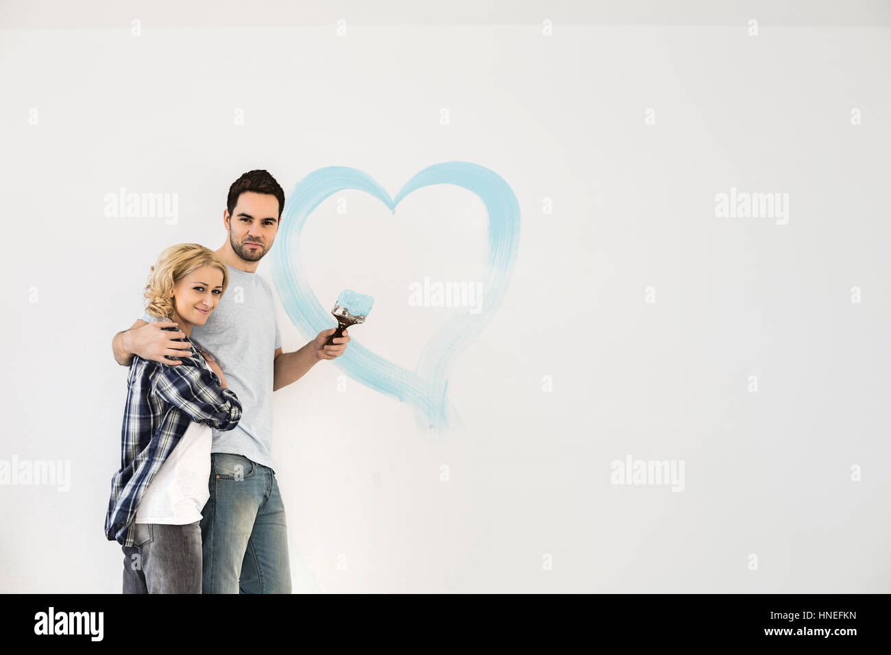 Porträt des mittleren Erwachsenenalter Liebespaar mit gemalten Herzen an Wand Stockfoto