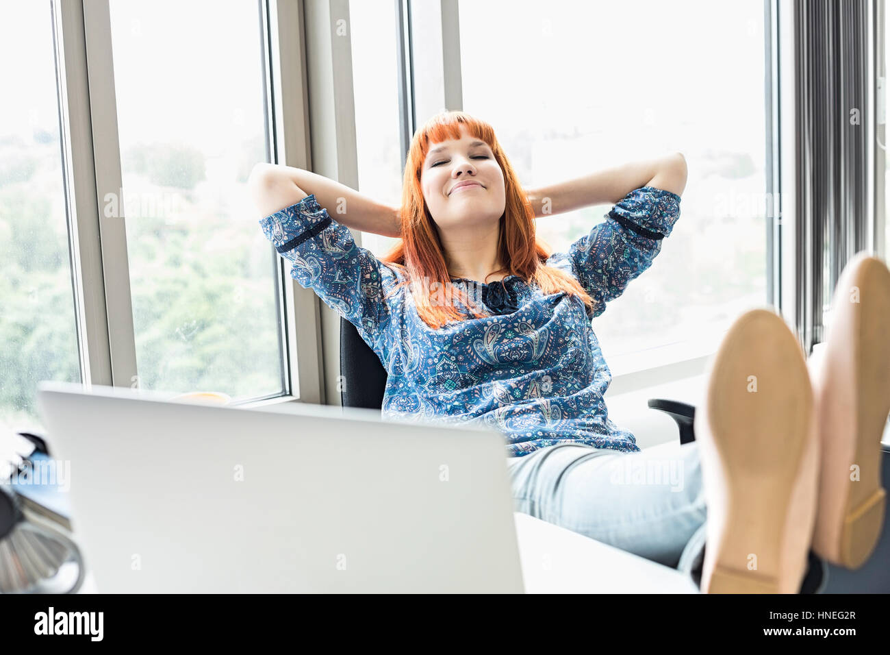 Geschäftsfrau mit Füße am Schreibtisch im Kreativbüro entspannen Stockfoto