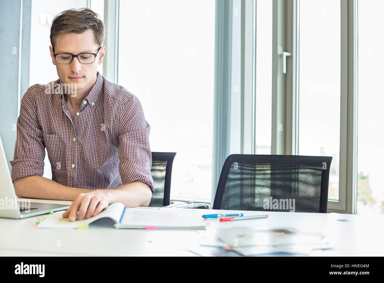 Kreative Geschäftsmann lesen Datei am Schreibtisch im Büro Stockfoto