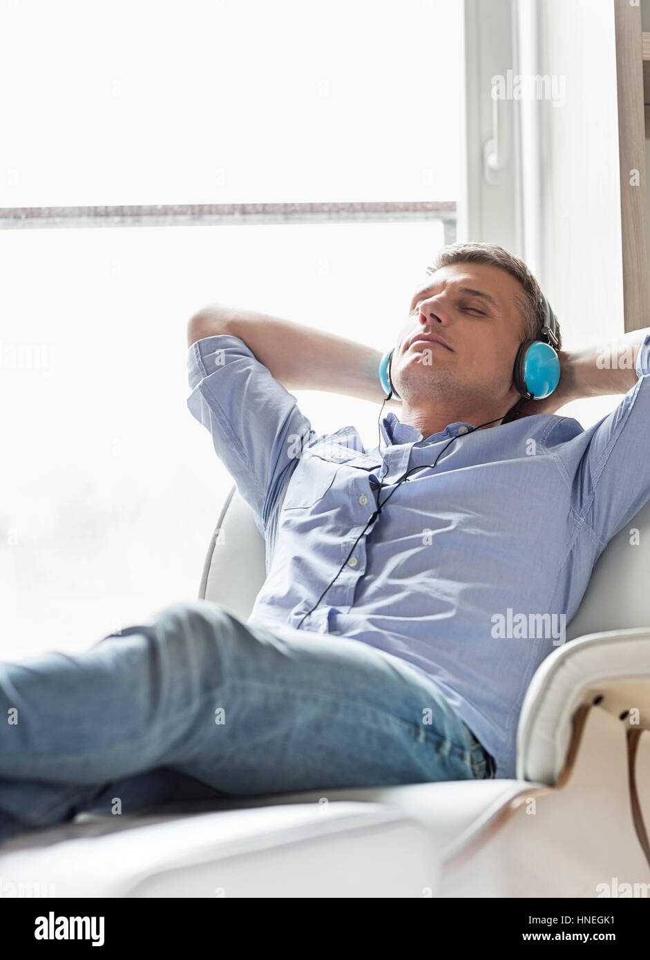 Entspannter Mann mittleren Alters Musikhören zu Hause Stockfoto