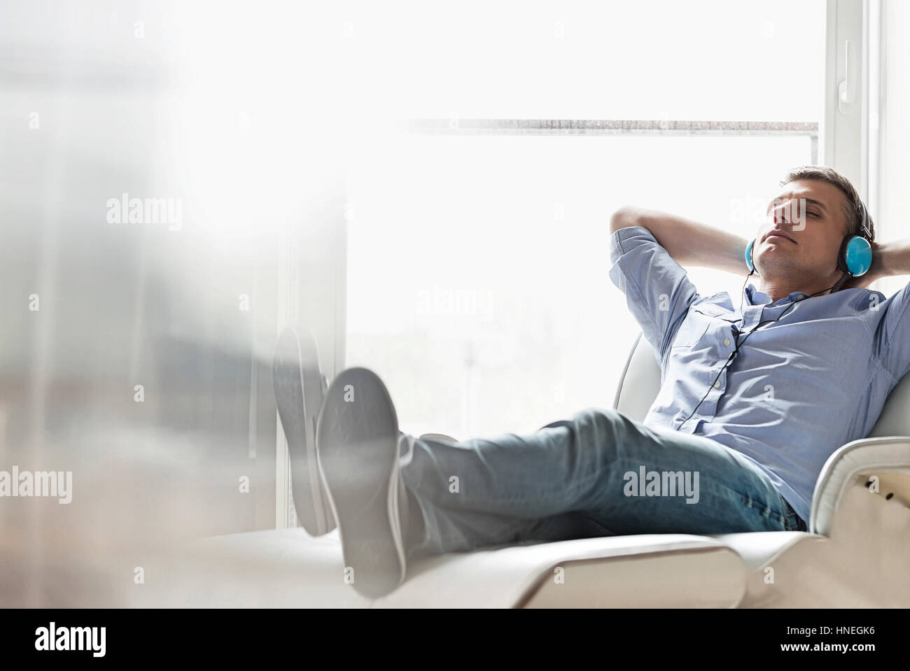 Der entspannte Mann mittleren Alters Musikhören zu Hause in voller Länge Stockfoto