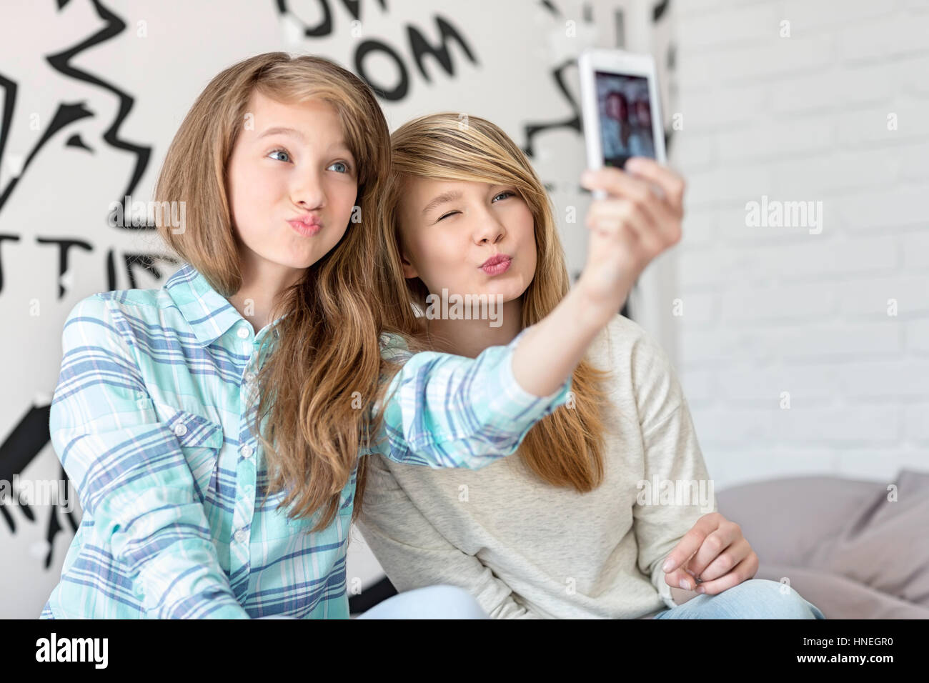 Nette Schwestern schmollend beim Fotografieren mit Ihrem Smartphone zu Hause Stockfoto