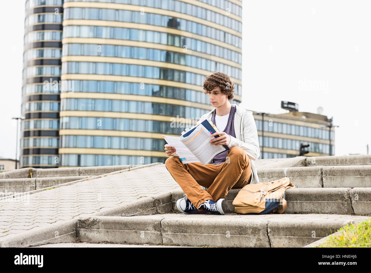 Volle Länge des jungen männlichen College Student Lesebuch gegen Gebäude Stockfoto