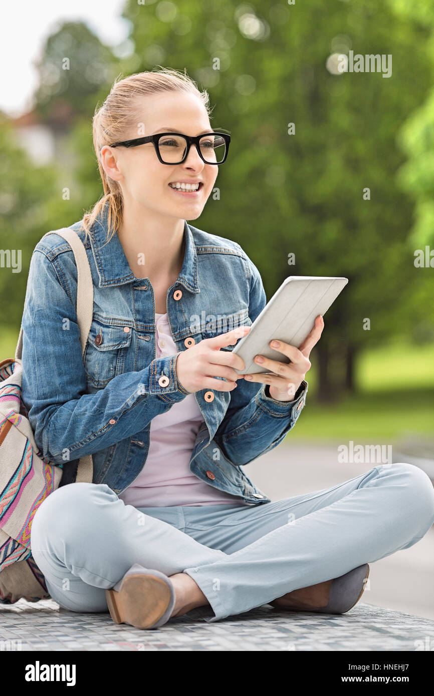 Voller Länge lächelnder junge weibliche Studentin mit Tablet PC im park Stockfoto