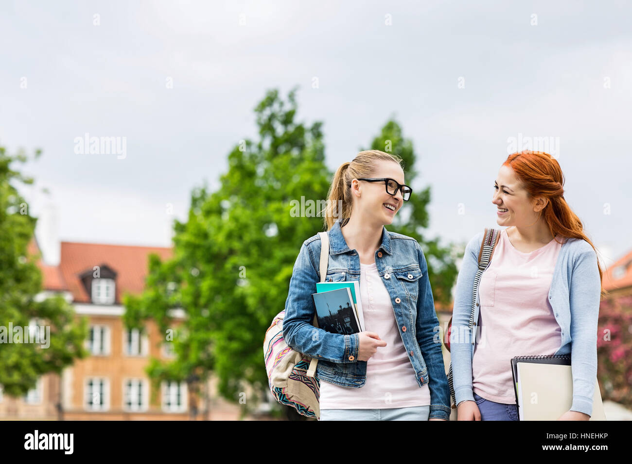 Lächelnde junge weibliche College-Freunde walking im freien Stockfoto
