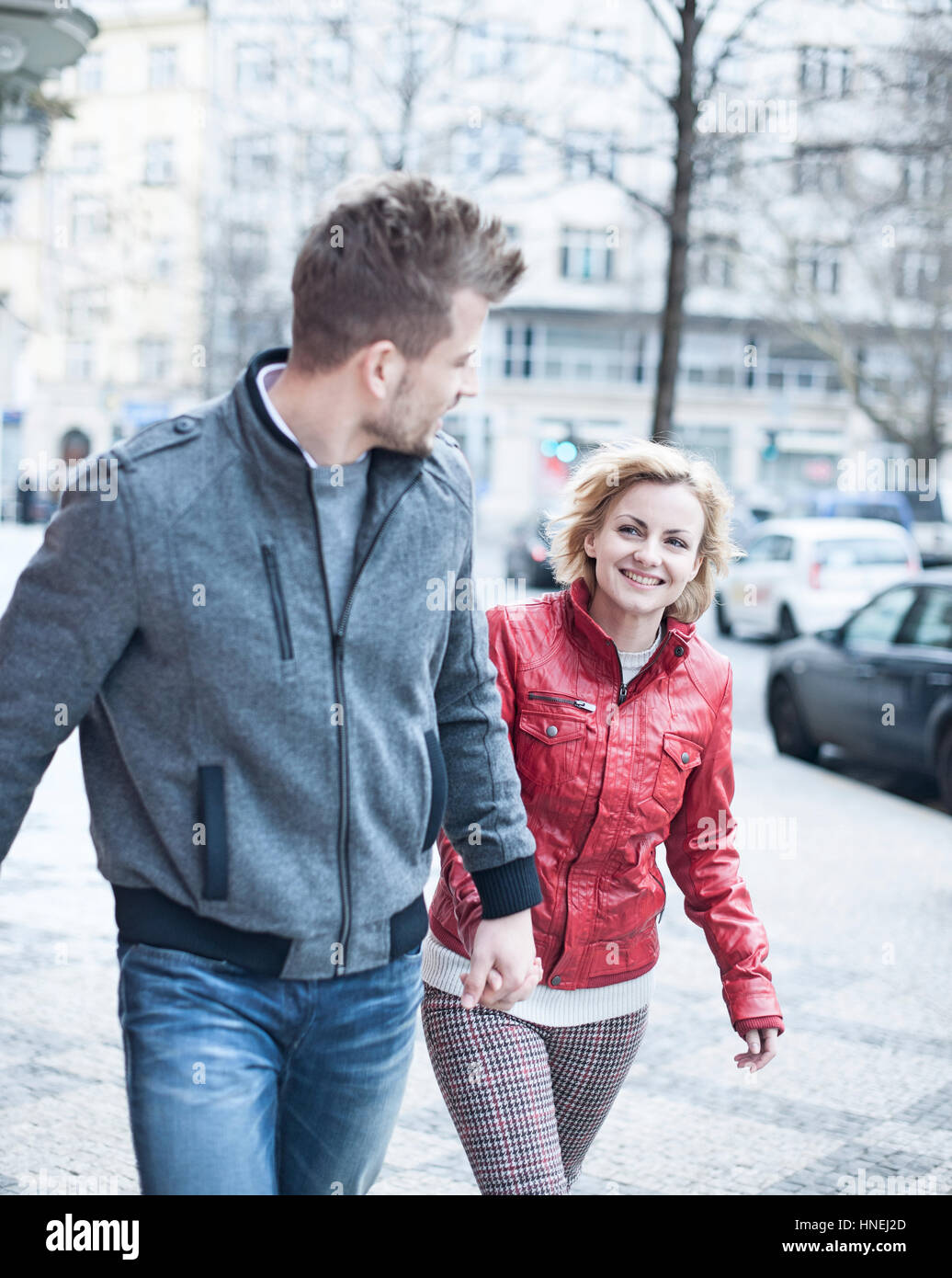 Glückliches junges Paar Hand in Hand während des Gehens auf Stadtstraße Stockfoto