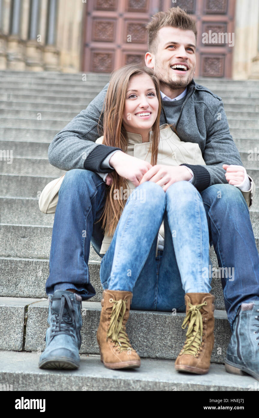 Volle Länge des jungen Paares auf Schritte im Freien sitzen Stockfoto