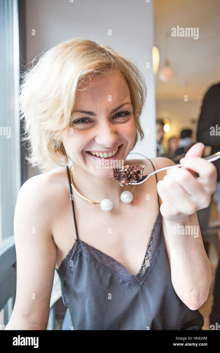 Porträt der glückliche junge Frau Essen Gebäck im café Stockfoto