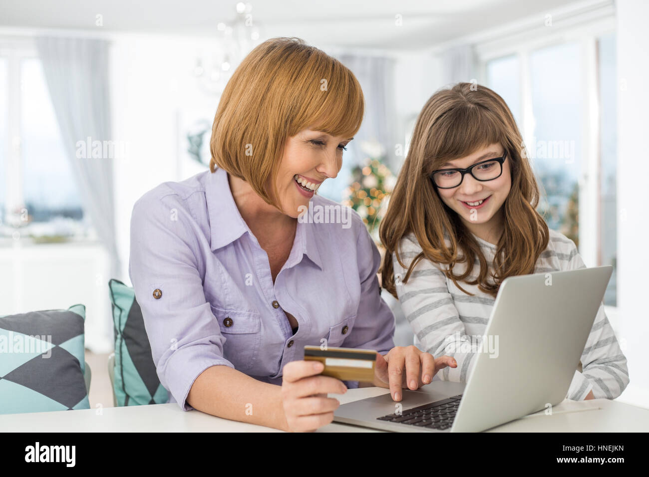 Fröhliche Mutter und Tochter in der Weihnachtszeit zu Hause online-shopping Stockfoto