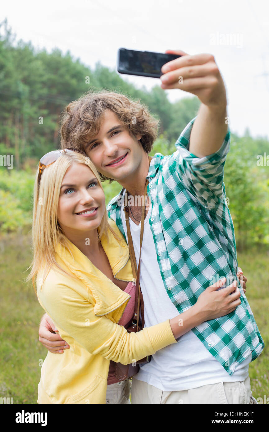 Glückliches junges Paar unter Selbstportrait durch Handy im Bereich Stockfoto