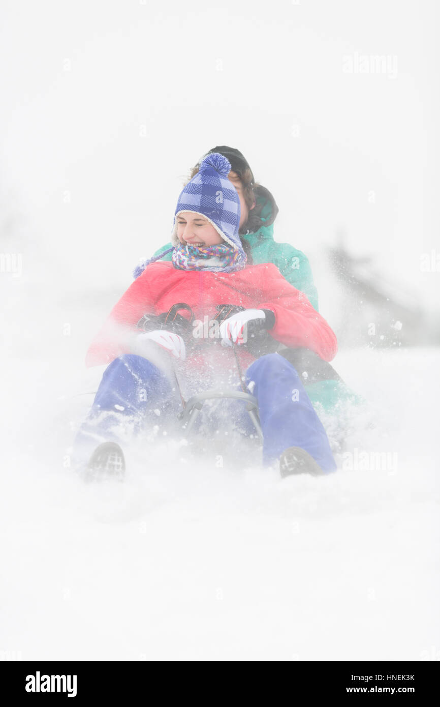 Fröhliches junges Paar im Schnee Rodeln Stockfoto