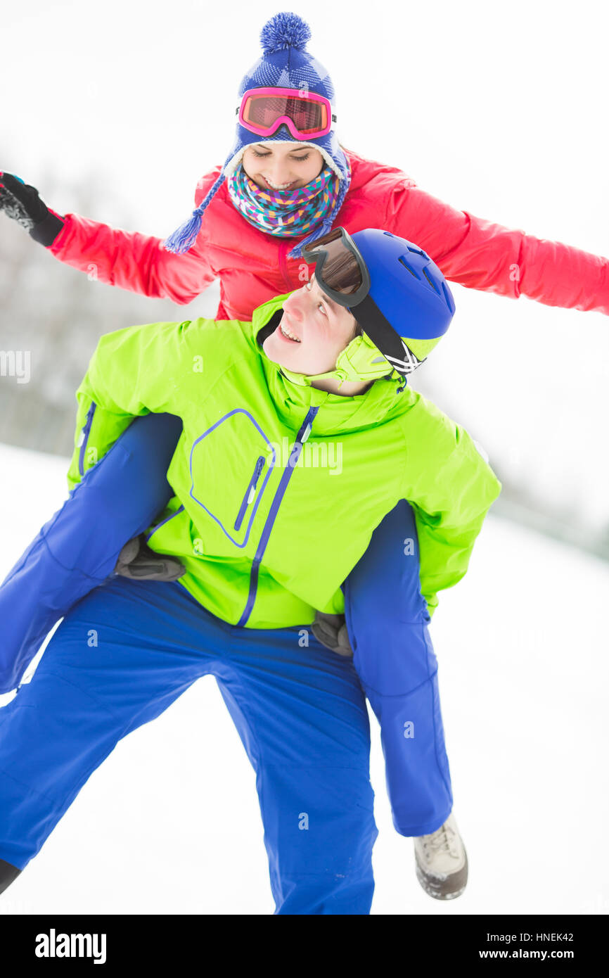 Glücklich Jüngling geben Huckepack Fahrt zur Frau im Schnee Stockfoto