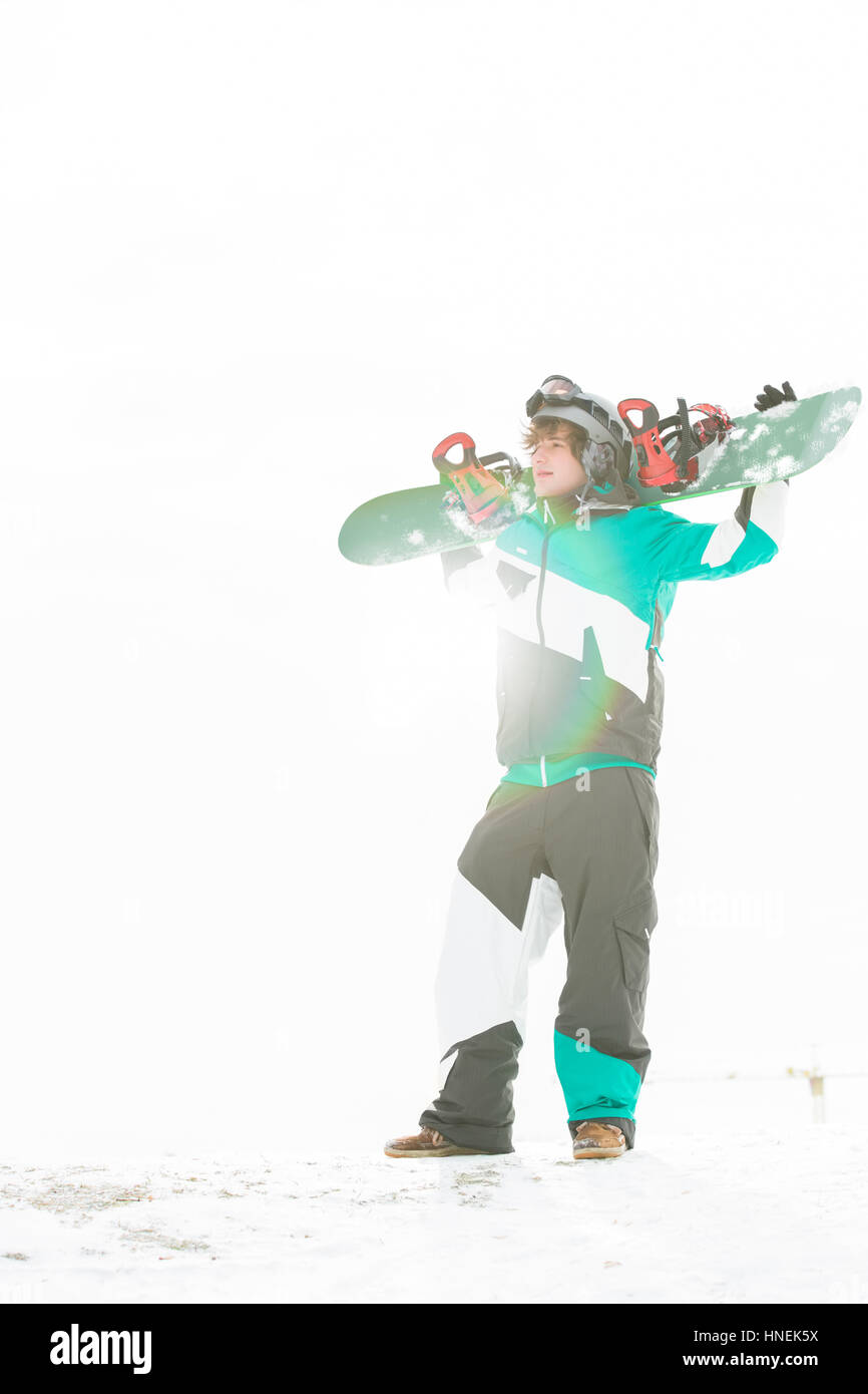 Gesamte Länge der junge Mann trägt Snowboard im Schnee Stockfoto