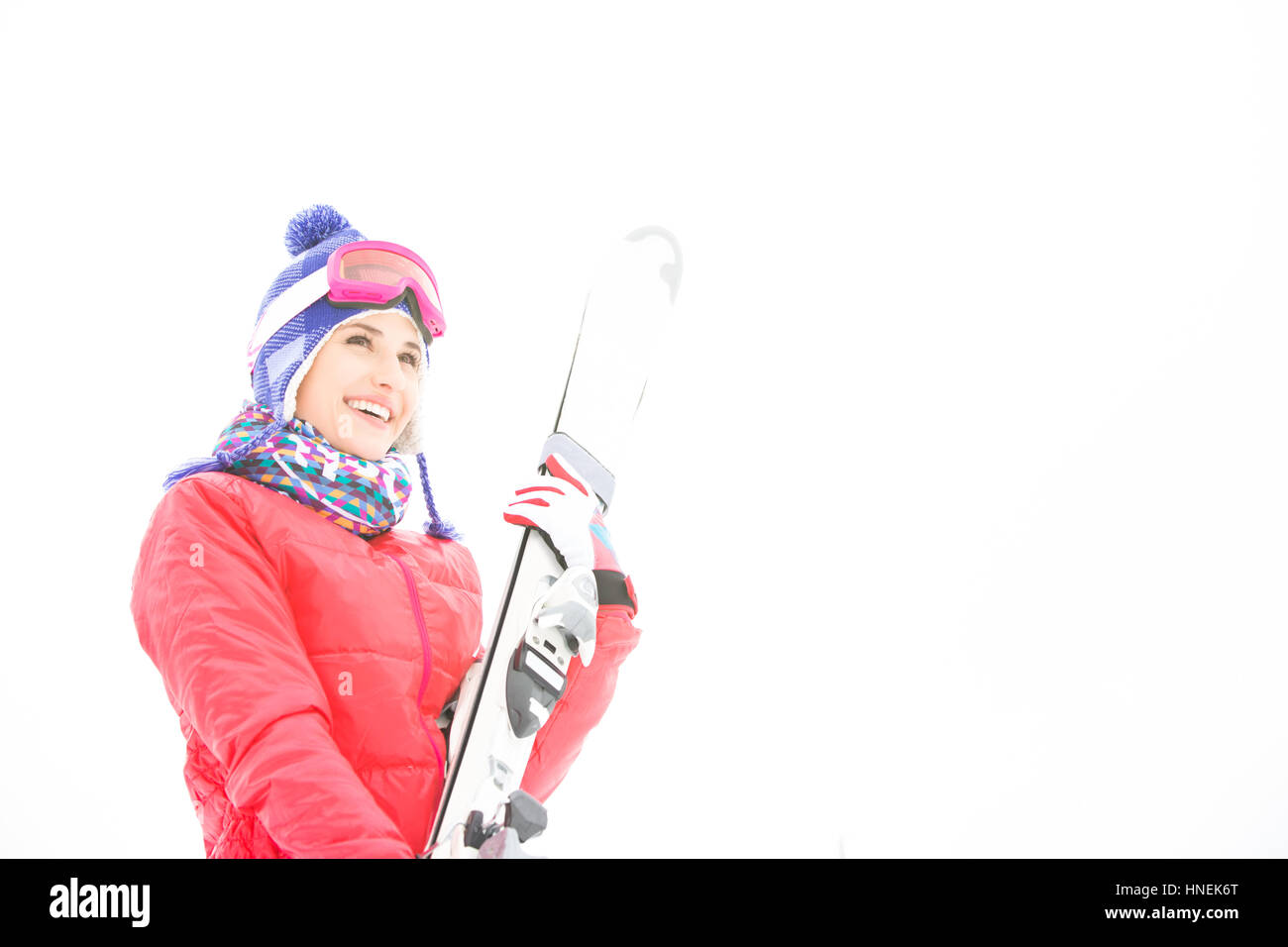 Lächelnde junge Frau mit Skiern im Schnee Stockfoto