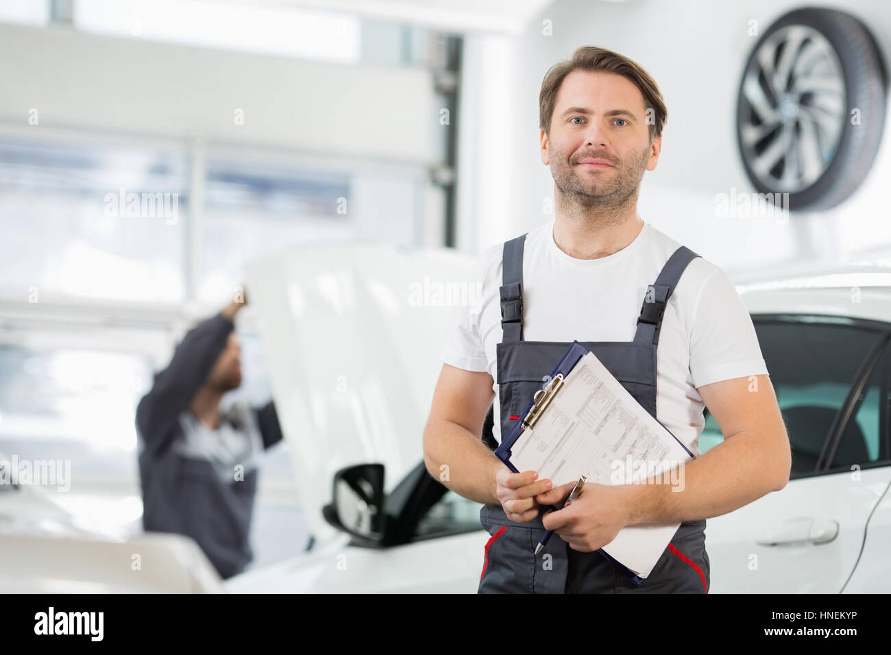 Porträt von zuversichtlich männlichen Instandhalter mit Zwischenablage in Auto-Werkstatt Stockfoto