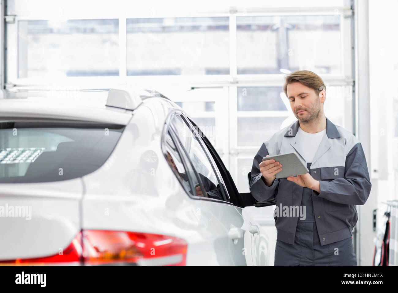 Männliche Reparatur Arbeitskraft mit Tablet PC im stehen mit dem Auto in die Werkstatt Stockfoto