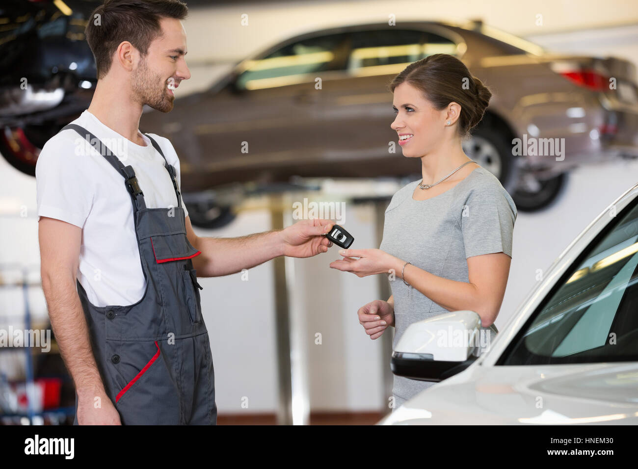 Glücklich Mechaniker geben Autoschlüssel zu Frau in Werkstatt Stockfoto