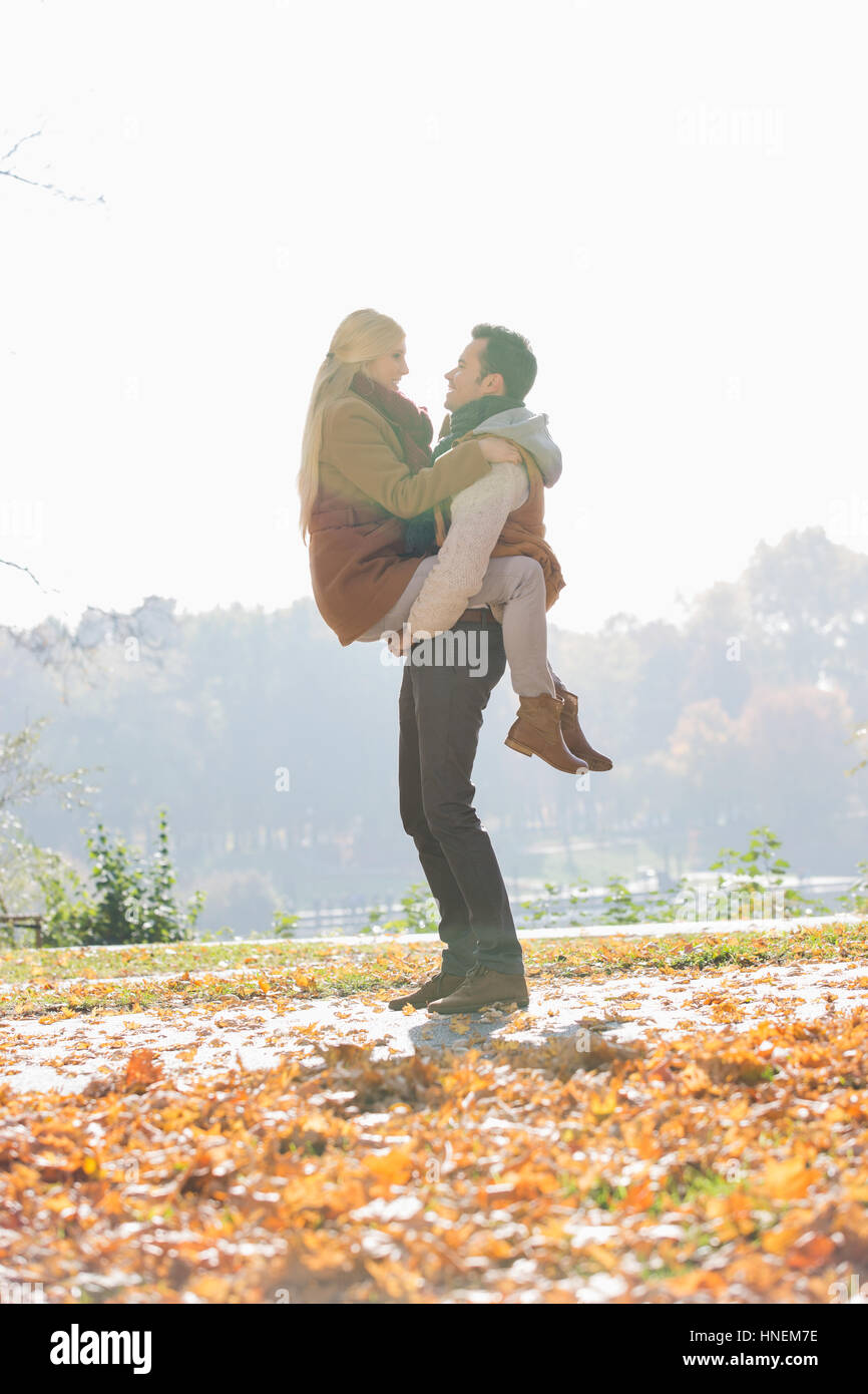 Junger Mann heben Frau im Park im Herbst Stockfoto
