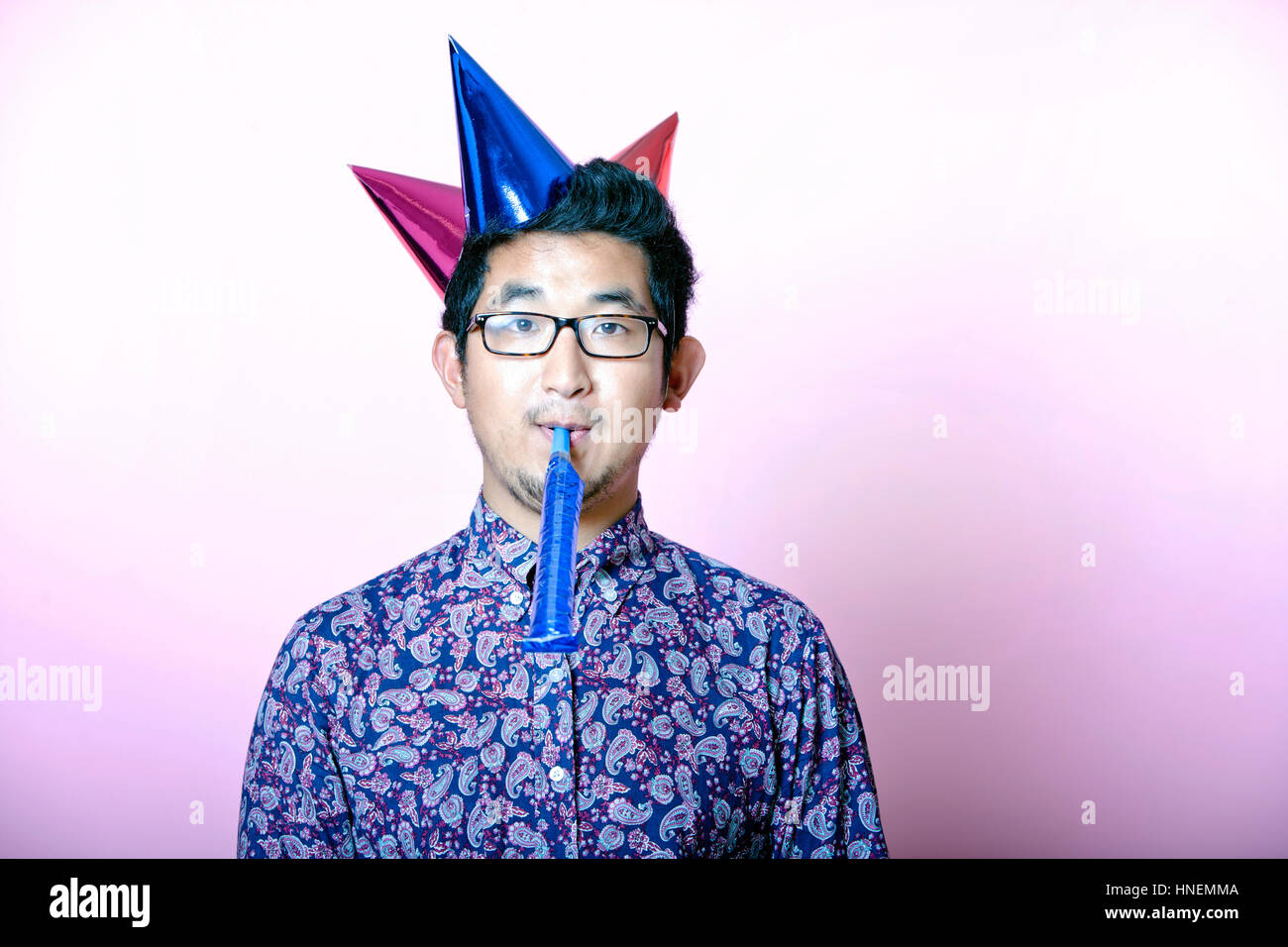 Geeky asiatischen Jüngling tragen viele Partyhüte Stockfoto