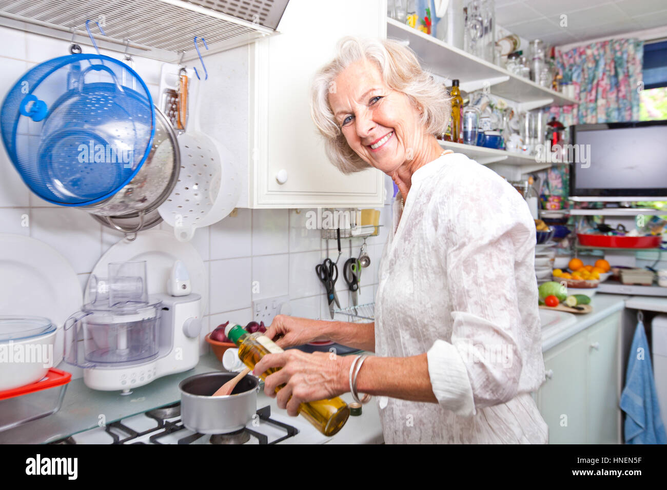 Porträt von senior Frau gießt Olivenöl Topf in der Küche Stockfoto