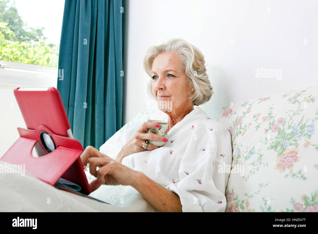 Ältere Frau mit digital-Tablette bei Kaffee am Bett zu Hause Stockfoto