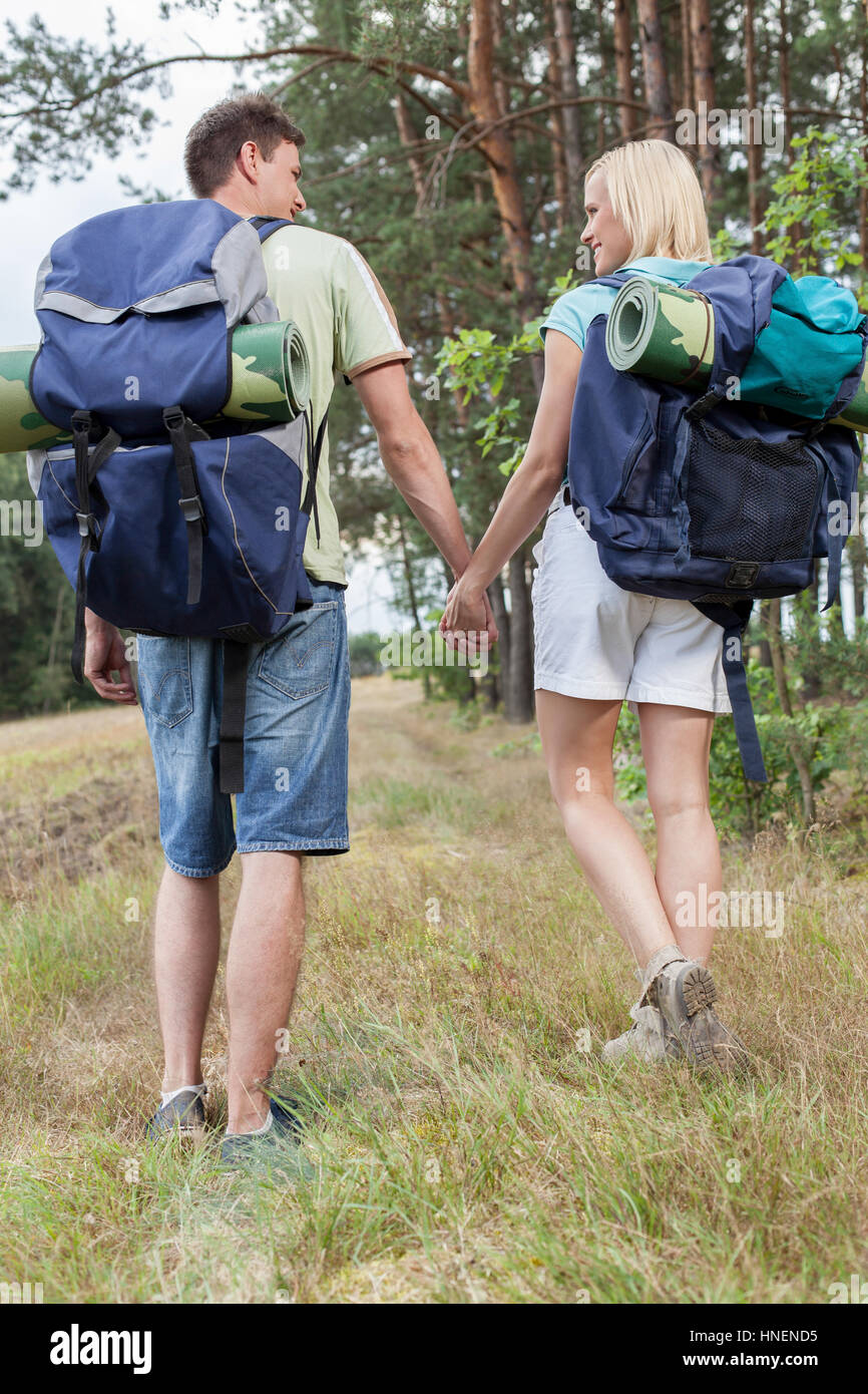 Voller Länge Rückansicht der junge Rucksacktouristen, die Hand in Hand in Landschaft Stockfoto