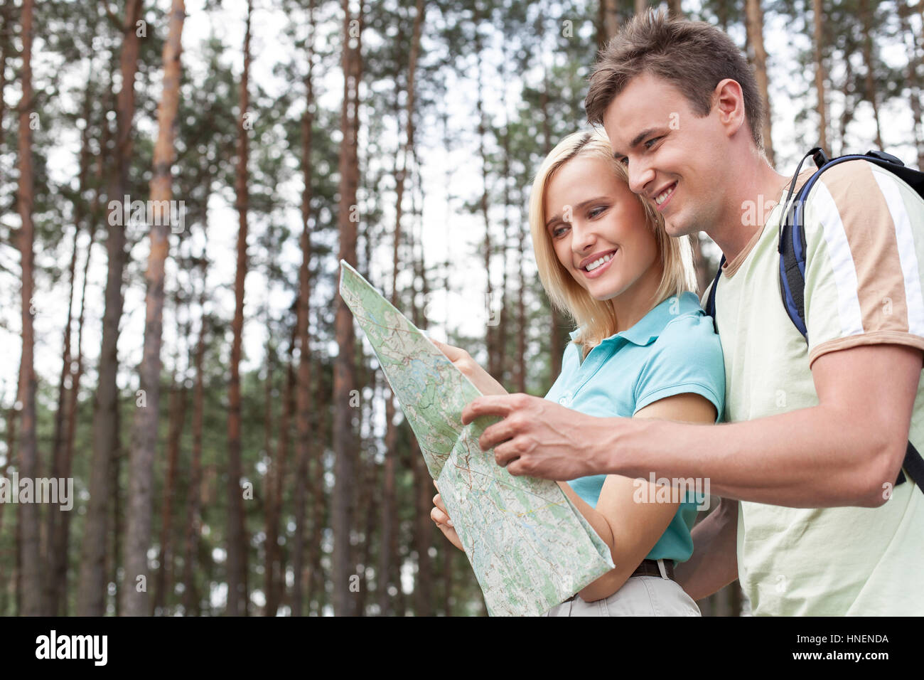 Glückliche junge Rucksacktouristen Blick auf Karte in Wäldern Stockfoto