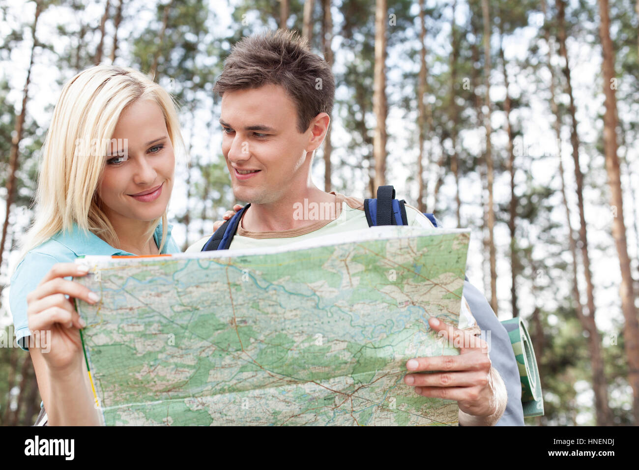 Glückliche junge Rucksacktouristen lesen Karte im Wald Stockfoto