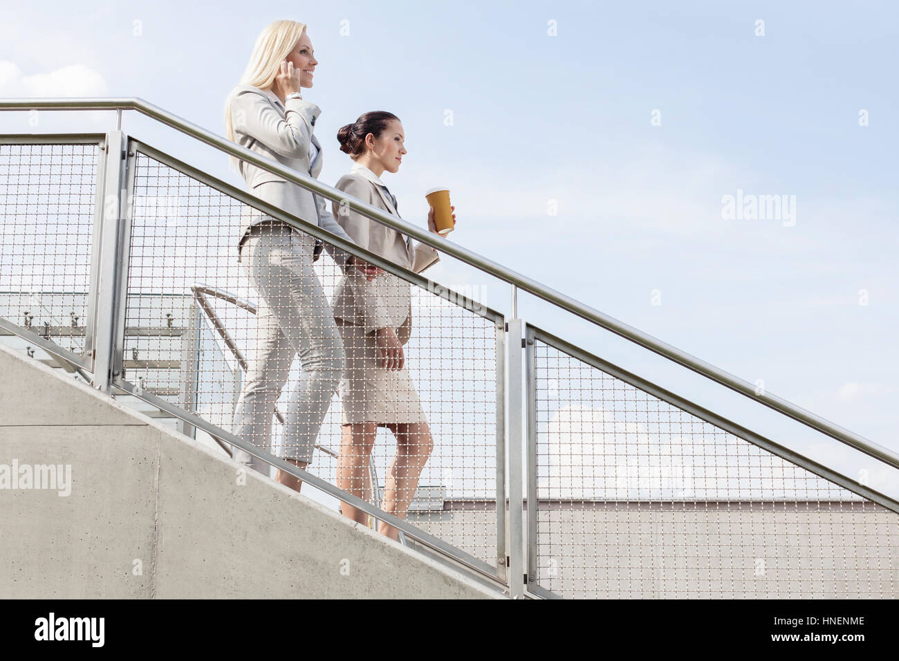 Profil-Schuss von Geschäftsfrauen hinunter Treppe gegen Himmel bewegen Stockfoto