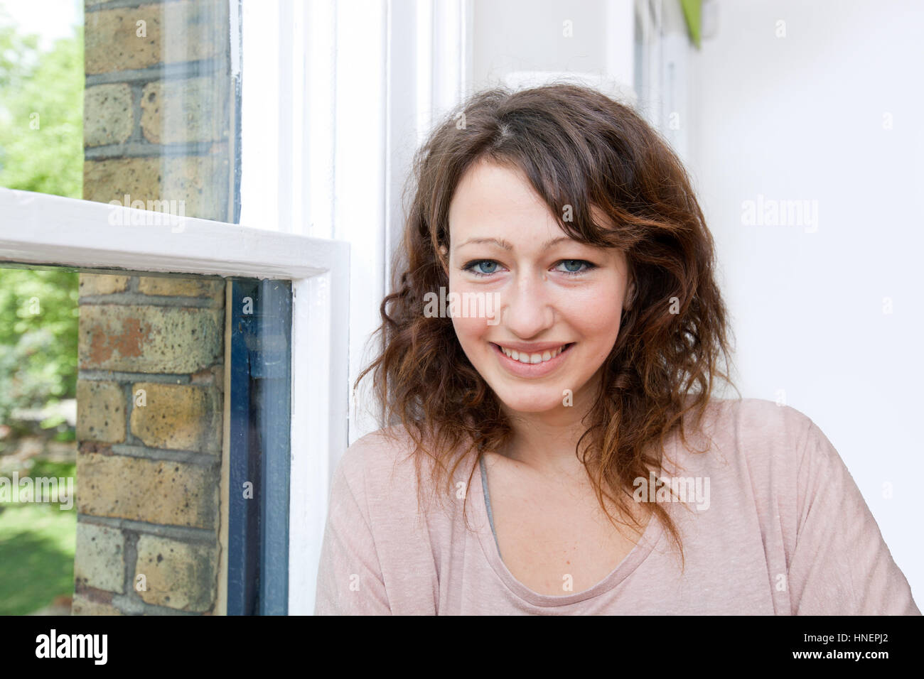 Junge Frau im trendigen Büro Blick in die Kamera und lächelnd Stockfoto