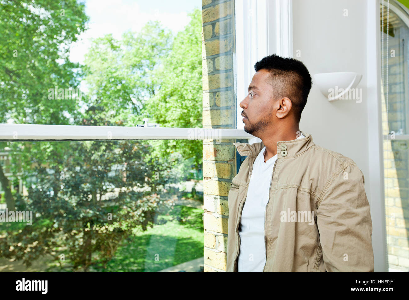 Junge indische Mann aus Fenster Stockfoto