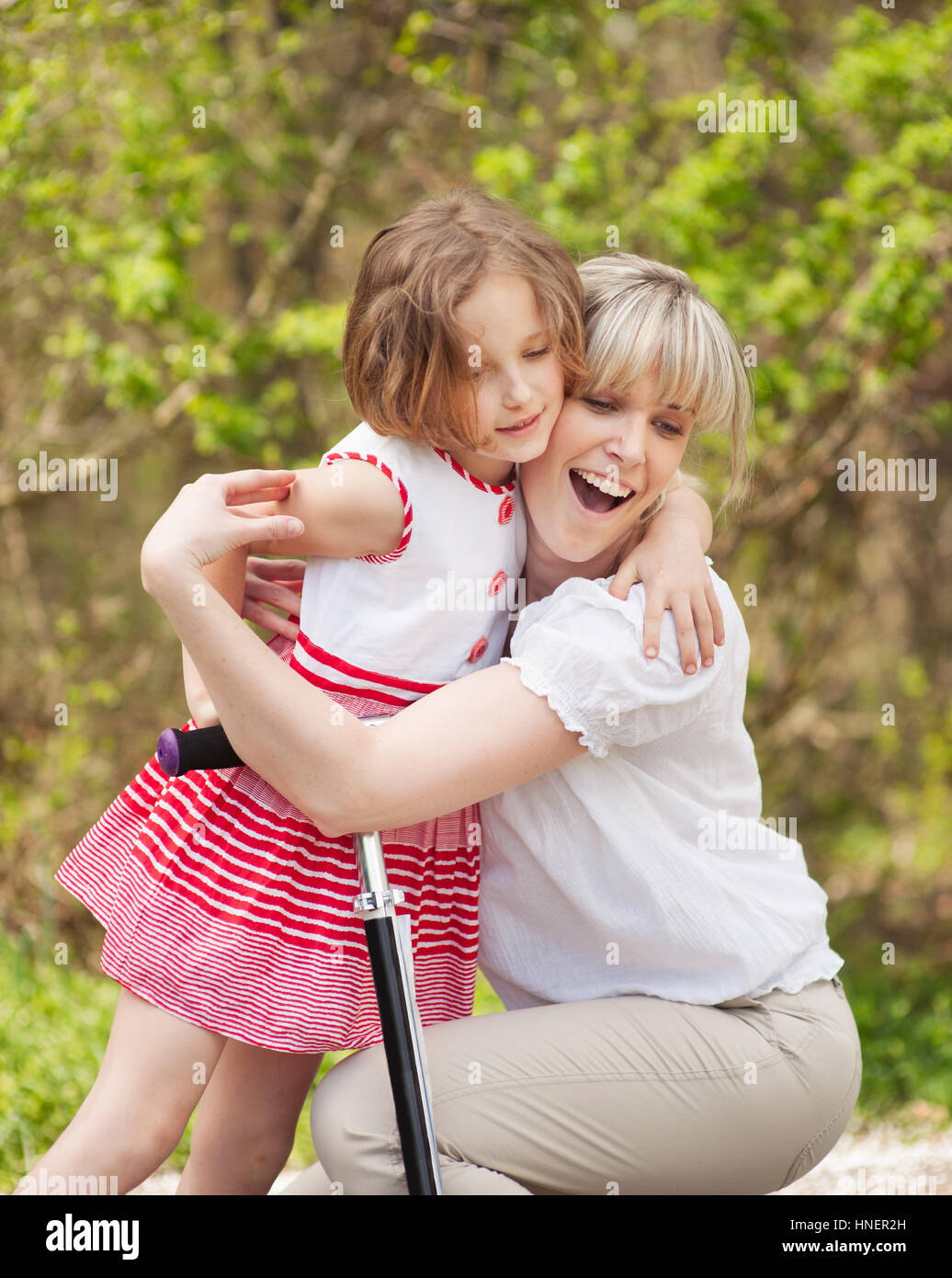 Mutter und Tochter hug im Park mit Roller Stockfoto