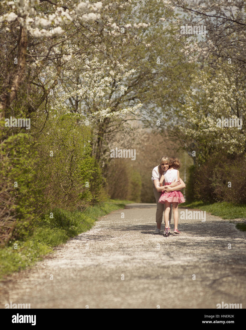 Mutter umarmt junge Mädchen in Ferne in einem park Stockfoto