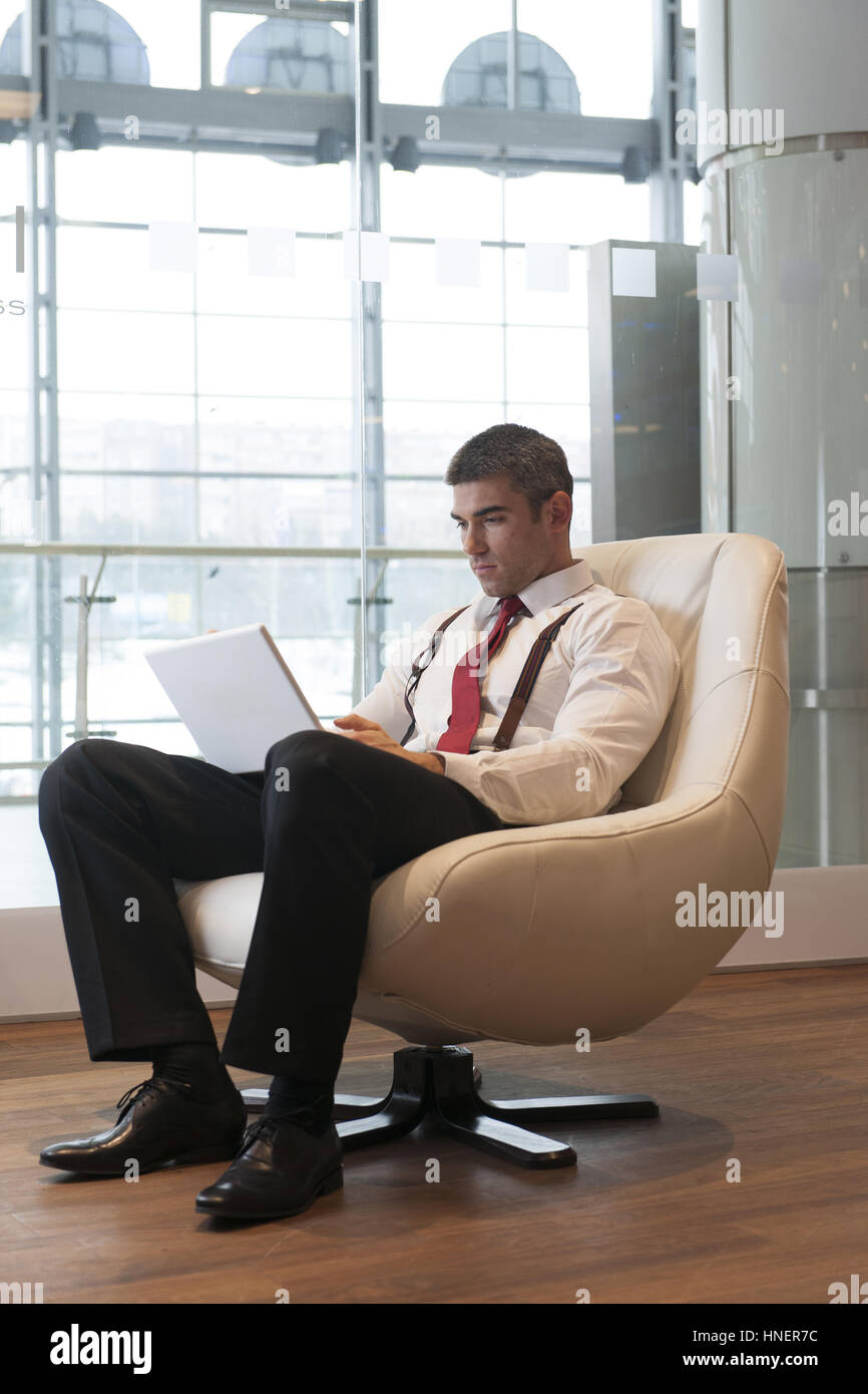Geschäftsmann in Sessel auf laptop Stockfoto