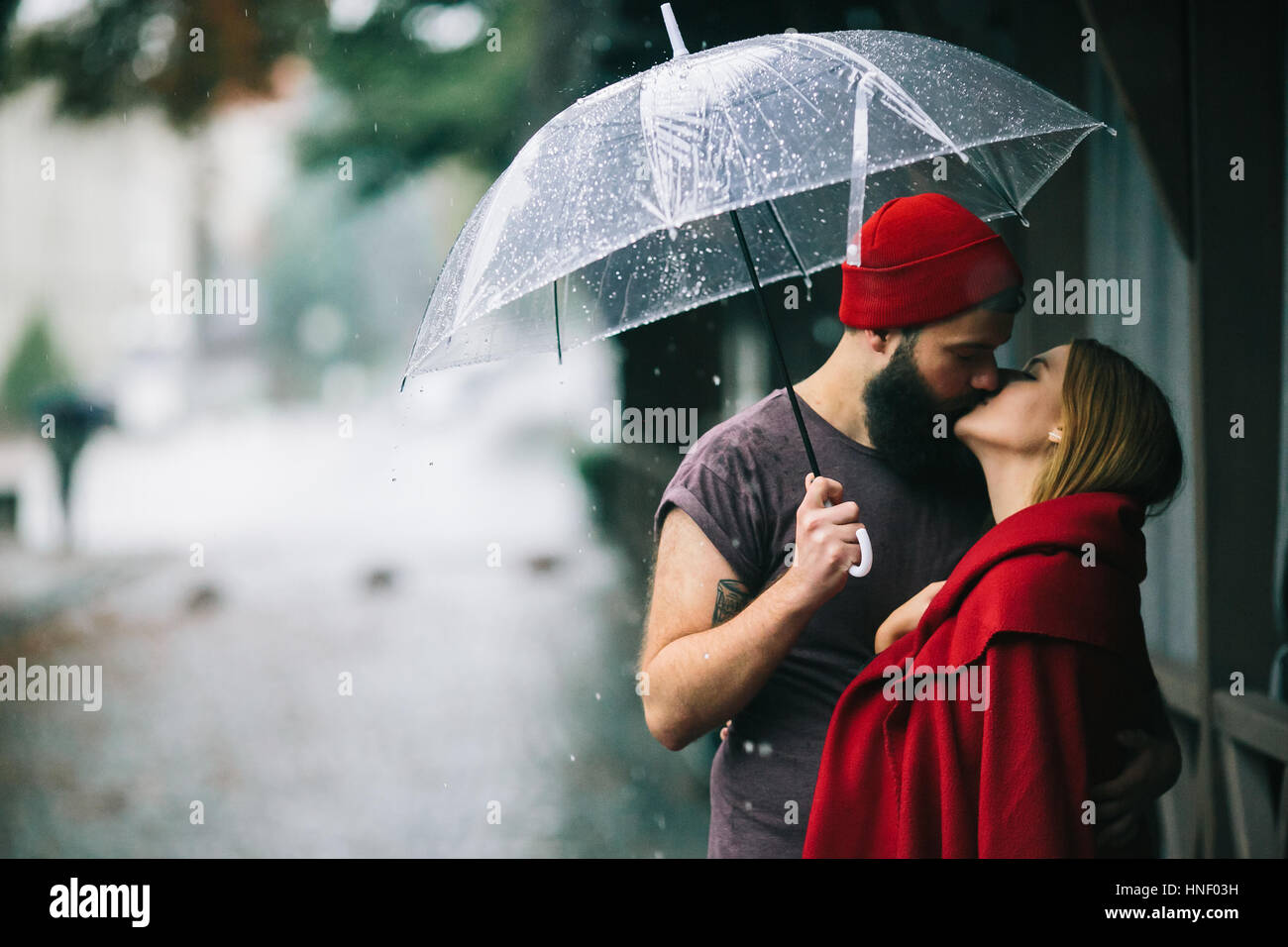Mann und das Mädchen küssen unter einem Regenschirm Stockfoto