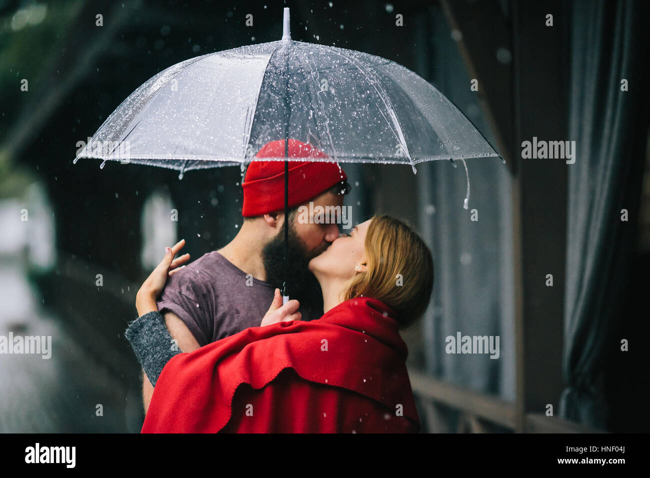 Mann und das Mädchen küssen unter einem Regenschirm Stockfoto