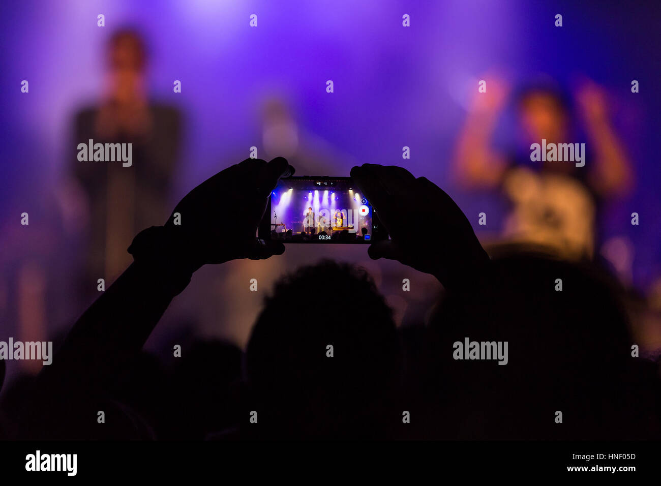 Besucher nehmen Foto mit Handy, Musiker auf der Bühne beim Konzert, Schweiz Stockfoto