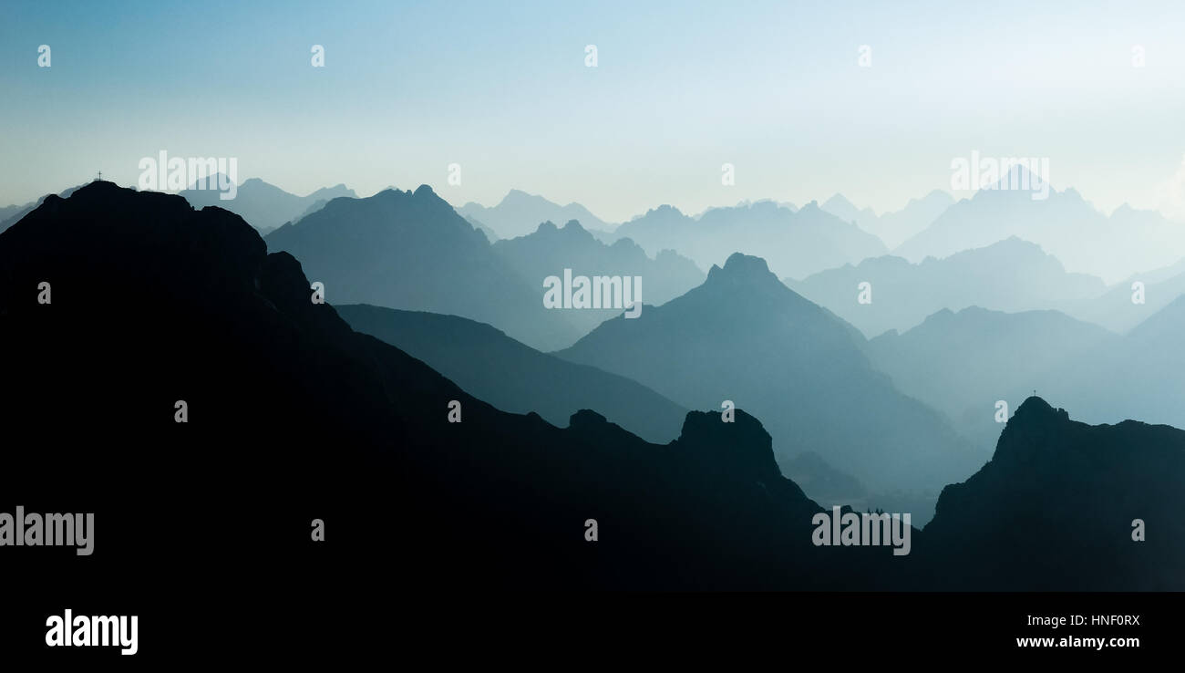 Spektakuläre blau und Cyan Bergketten Silhouetten. Summit Kreuze sichtbar. Stockfoto