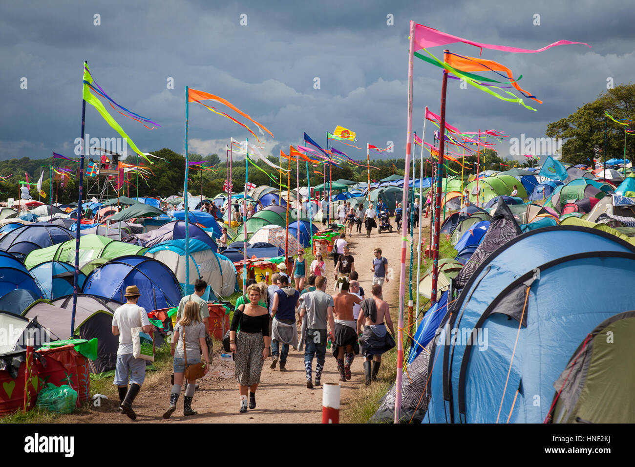 GLASTONBURY, UK - 27. Juni 2014: Menschen zu Fuß durch einen Campingbereich mit Colouful Fahnen beim Glastonbury Festival 2014 Stockfoto