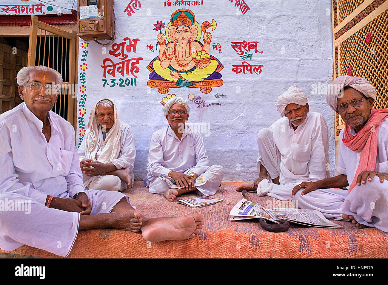 Freunde stehen vor einer Hauswand mit Wandmalereien von Gott Ganesh und indischen Skript Sanskrit, Jaisalmer, Rajasthan, Indien gemalt Stockfoto