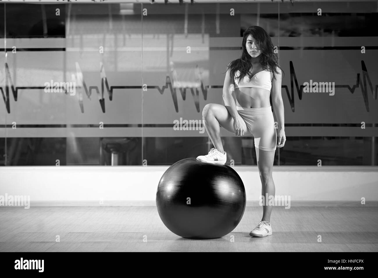 Asiatin mit Fitness-Ball im Fitnessstudio schwarzen und weißen Farben. Chinesin im Fitnessclub Stockfoto