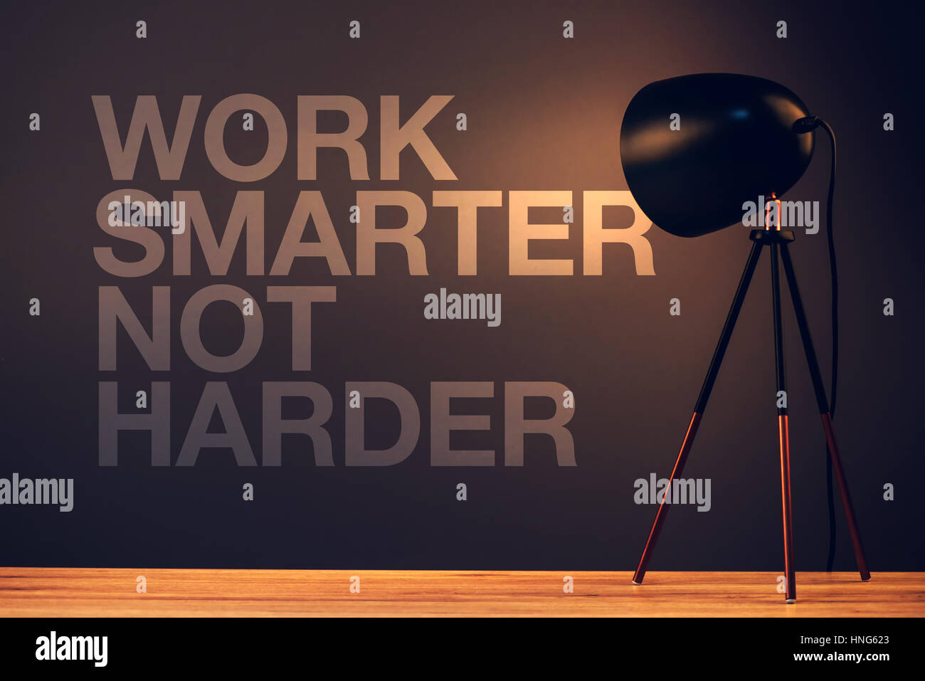Arbeit intelligenter nicht härter, Motivations-Quote an Bürowand mit Schreibtischlampe beleuchtet Stockfoto