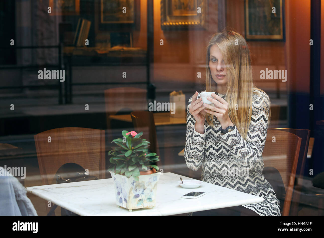 Frau mit einer Tasse Kaffee. Städtischen Schuss durch das Fenster Stockfoto